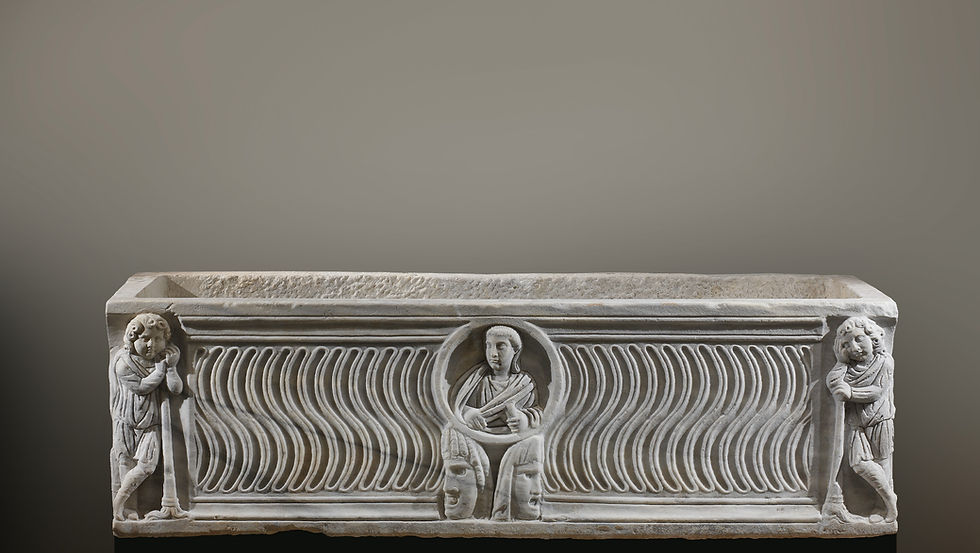 Roman marble sarcophagus with strigil (wave-pattern) fluting, a central medallion portrait bust above two theatre masks, and mourning genii holding reversed torches at each corner, 1st half of 3rd century AD, reworked early 4th century AD.