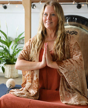 Melanie Dean in prayer pose before a Paiste symphonic gong, preparing for a Kundalini Meditation and gong bath session
