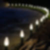 Warm white C9 Christmas lights installed along a stone landscape border