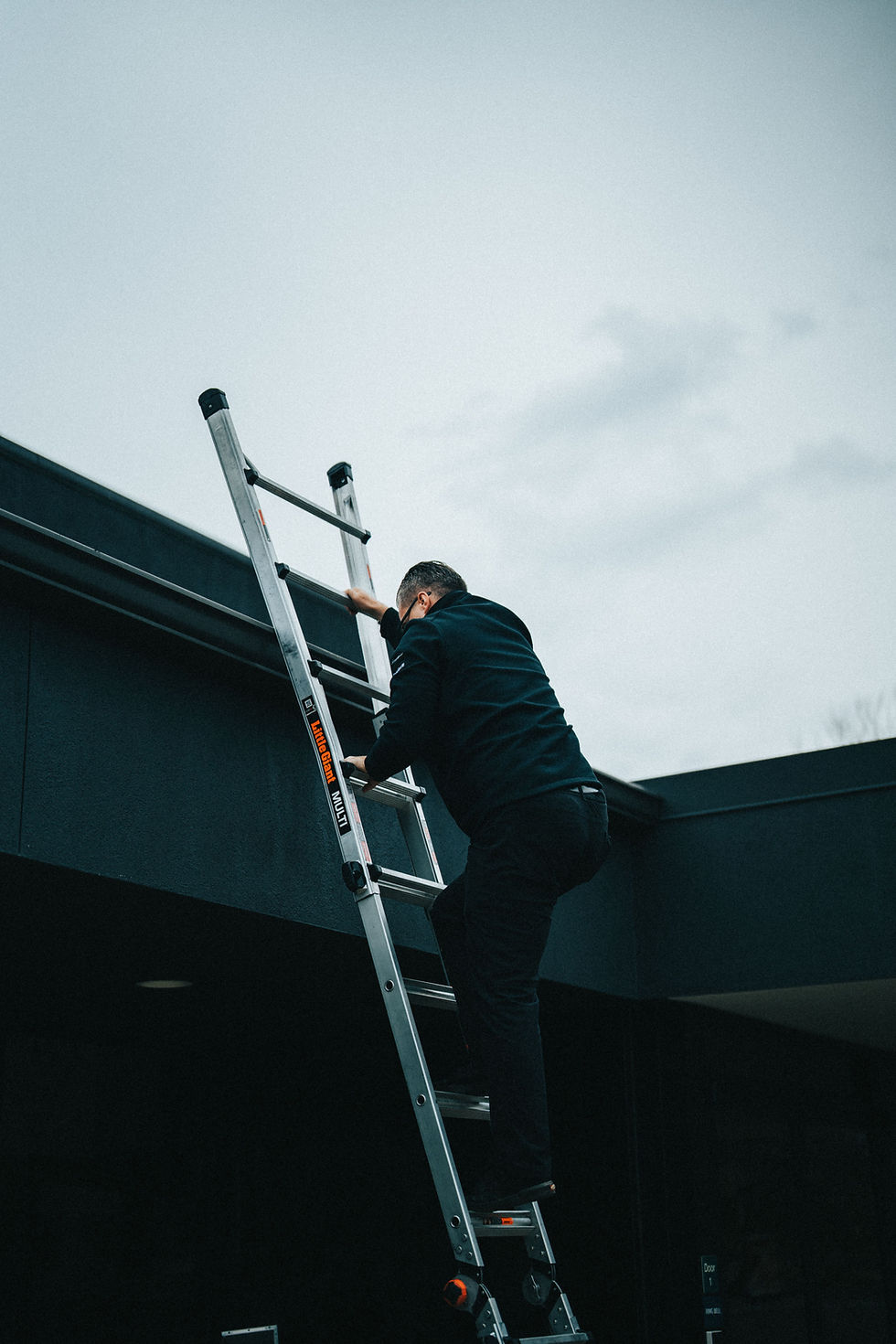Person climbing an extension ladder during an outdoor installation