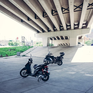 Two motorcycles parked under the freeway 94 East.