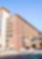 A brick and glass parking garage building with a bridge attached to another building.