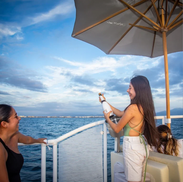 woman opening champaign bottle ona catamran