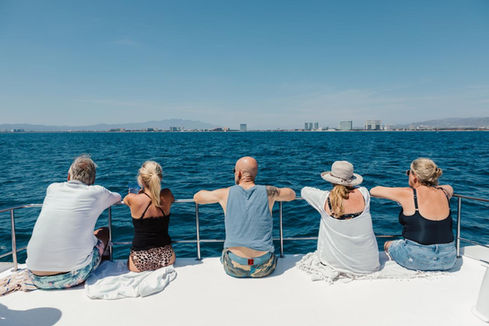 5 people sitting on the rails of a catamaran