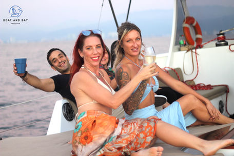 Two women and a man celebrating on a sailboat