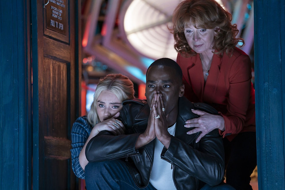 Ruby, the Doctor and Mel all looking upset looking out of the TARDIS