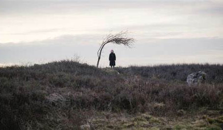 A creepy woman in the distance, well, 73 yards away. She is on a grassy clifftop