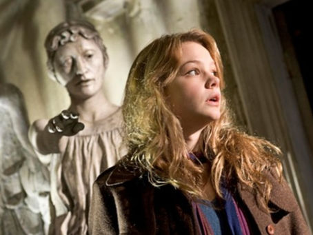 Sally looking away as a Weeping Angel reaches out behind her