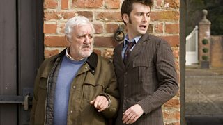 Wilfred and the doctor hiding behind a wall