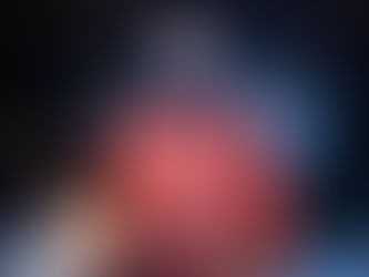 The Doctor looking focused in orange spacesuit. Fire at bottom of screen. He is about to cause some serious shit