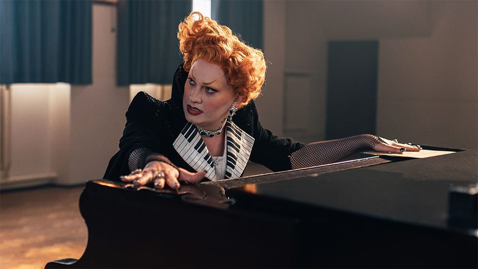 Maestro sat at piano, hands resting on the top