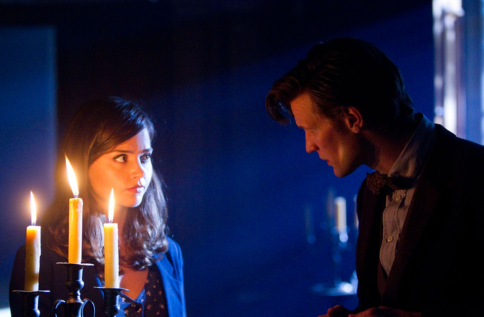 Clara and the Doctor looking at each other by candle light