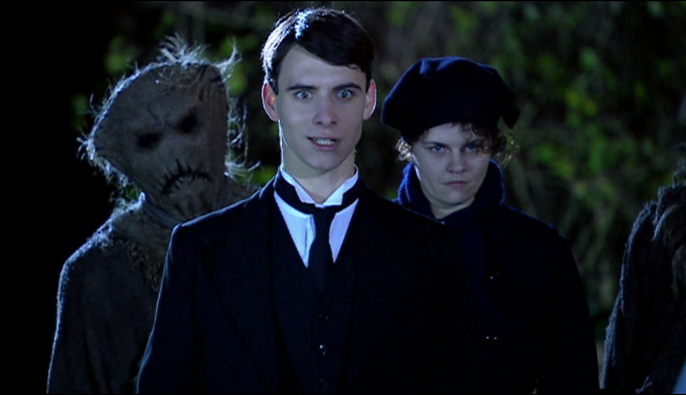 Creepy scarecrow behind Baines and Jenny