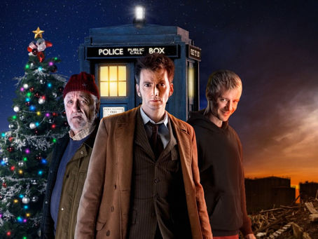 Promo image for The End of Time. The TARDIS and a christmas tree behind the Doctor in long brown coat, The Master all in black and Wilf in a red winter hat