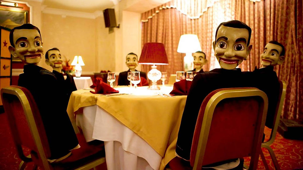 Creepy dolls looking at the camera. They are sat at a table in a hotel restaurant