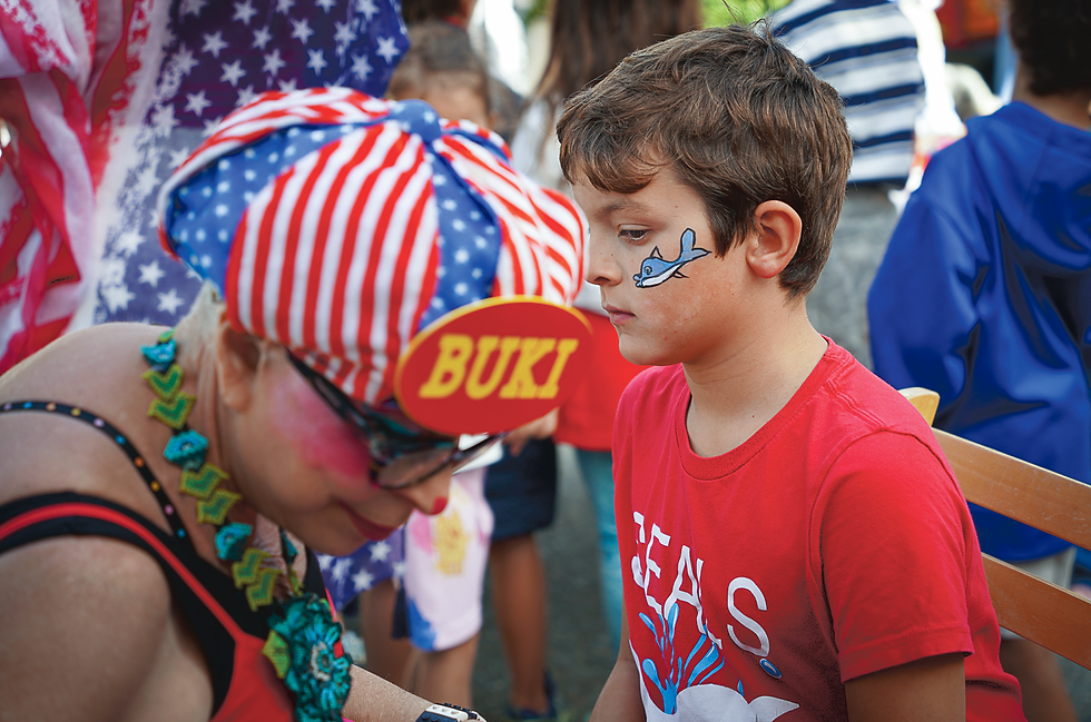 Tiburon marked the nation’s 250th anniversary of independence on July 4 with a downtown block party on lower Main Street, organized by the town and the Tiburon Peninsula Chamber of Commerce. Debbie Boeger brought her dog, Twinkle Little Star, and a flag-decked ‘USA’ wagon to the Pooch Parade, which led costumed dogs from Beach Road along Ark Row to Fountain Plaza. Sonoma rock band Gas Money performed for the crowd, while Buki the Clown painted a shark on the face of a young reveler on Ark Row. Crowds later gathered at Shoreline Park to watch San Francisco’s fireworks, launched from the Golden Gate Bridge, though fog obscured much of the show. (Ted McDonnell / For The Ark)