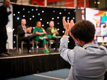 Back of man clapping in front row of SaferToBeMe conference