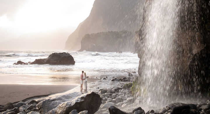 Maternity photography in Madeira featuring a pregnant woman near a waterfall and ocean cliffs