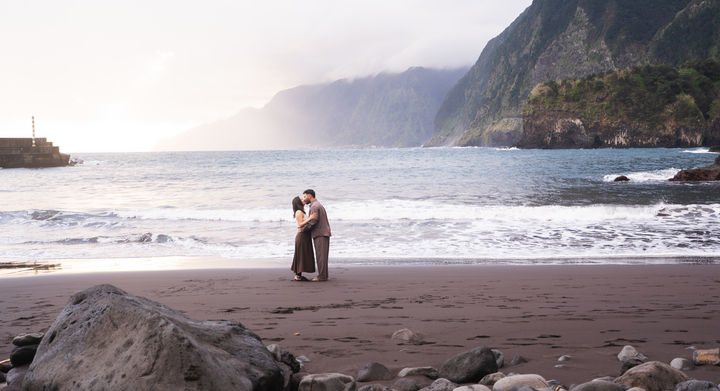 Couple embracing on Seixal black sand beach during a romantic proposal photoshoot in Madeira