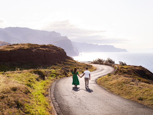 Romantic couple photoshoot in Caniçal Madeira – walking hand in hand on a scenic coastal road with ocean view