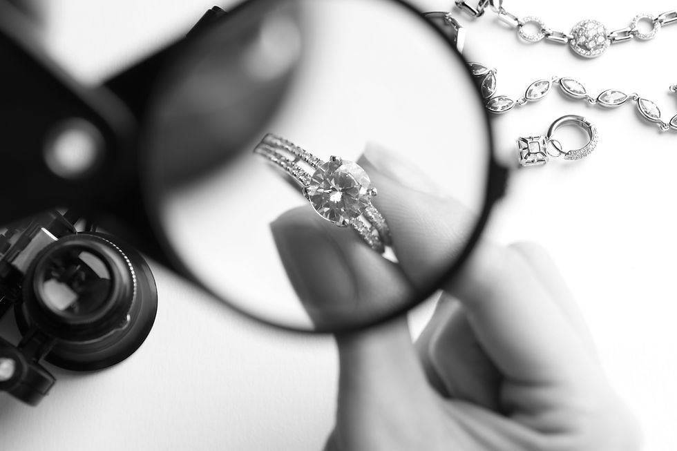 Jeweler examining diamond ring with magnifying glass at white table, closeup_edited.jpg