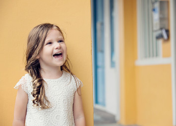 Young girl laughing in front of a colorful wall – candid children’s photography in Singapore