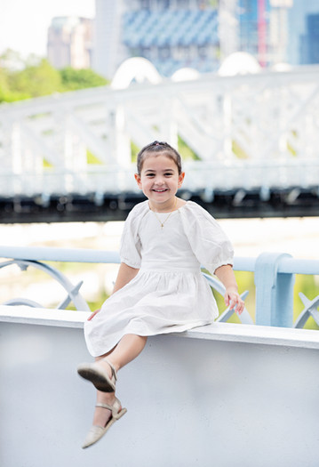 Young girl sitting on a bridge at Fullerton Hotel – children’s photography Singapore
