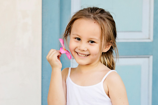 Young girl holding a toy and smiling – vibrant children’s photography Singapore