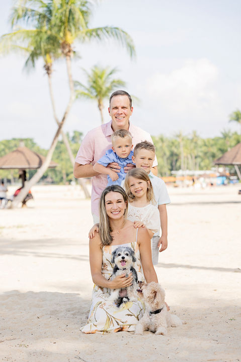 Family sitting together on the beach surrounded by greenery in Singapore during a natural and candid family photoshoot