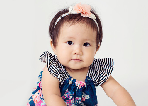 Toddler girl sitting outdoors with a bow in her hair – baby photography Singapore
