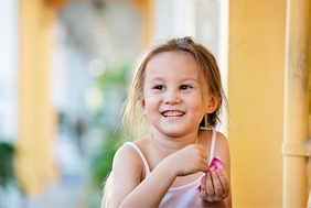 Young girl leaning against a yellow wall in Joo Chiat Place – children’s photography Singapore
