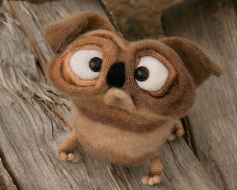 Crochet pug puppy with big eyes on a wooden plank