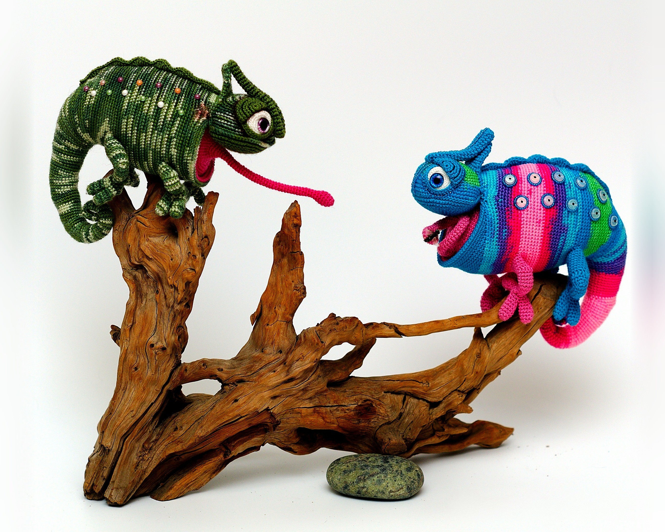 Two crochet chameleons on a piece of driftwood