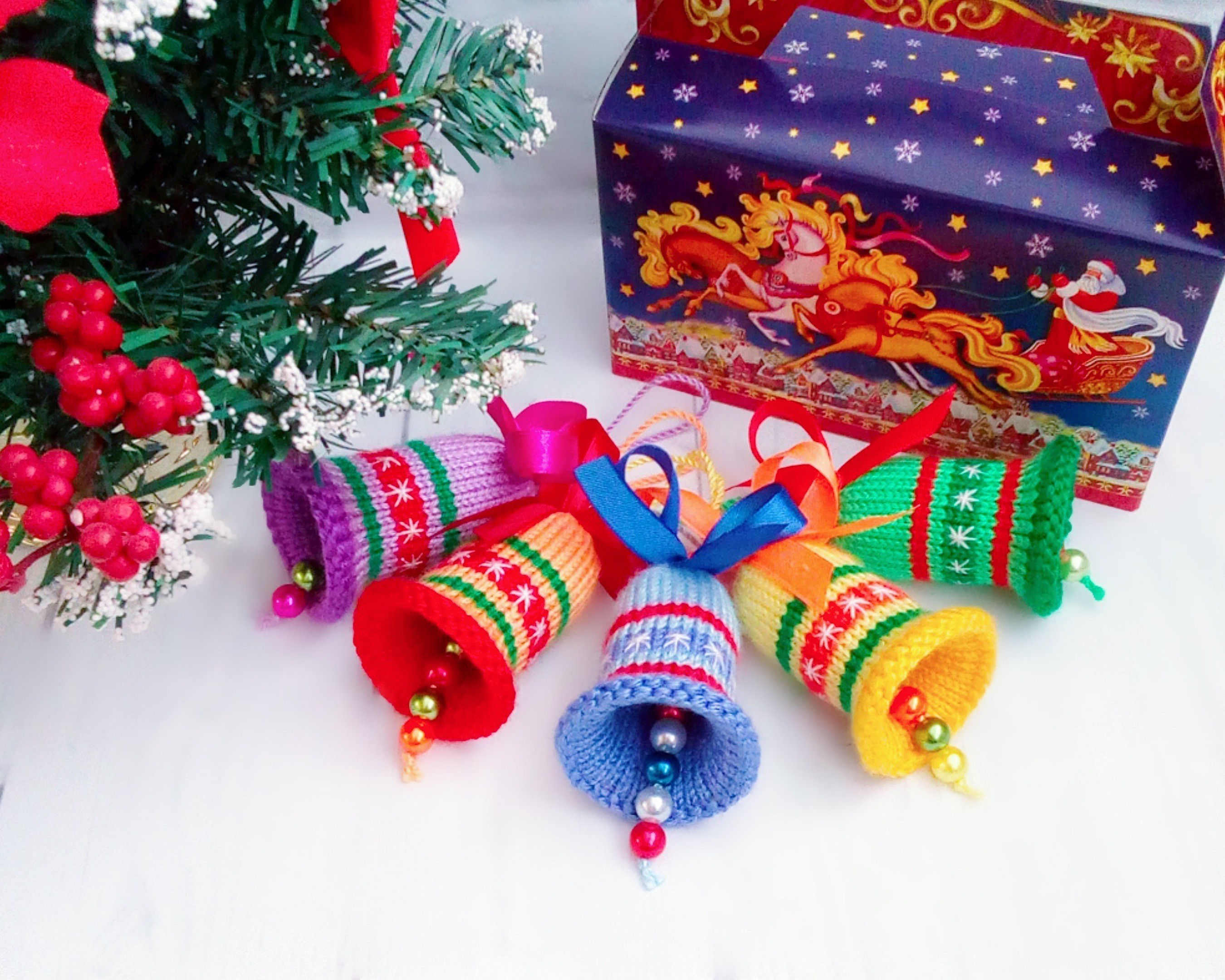 Gebreide gestreepte kerstbellen met strikken bij een cadeaudoos