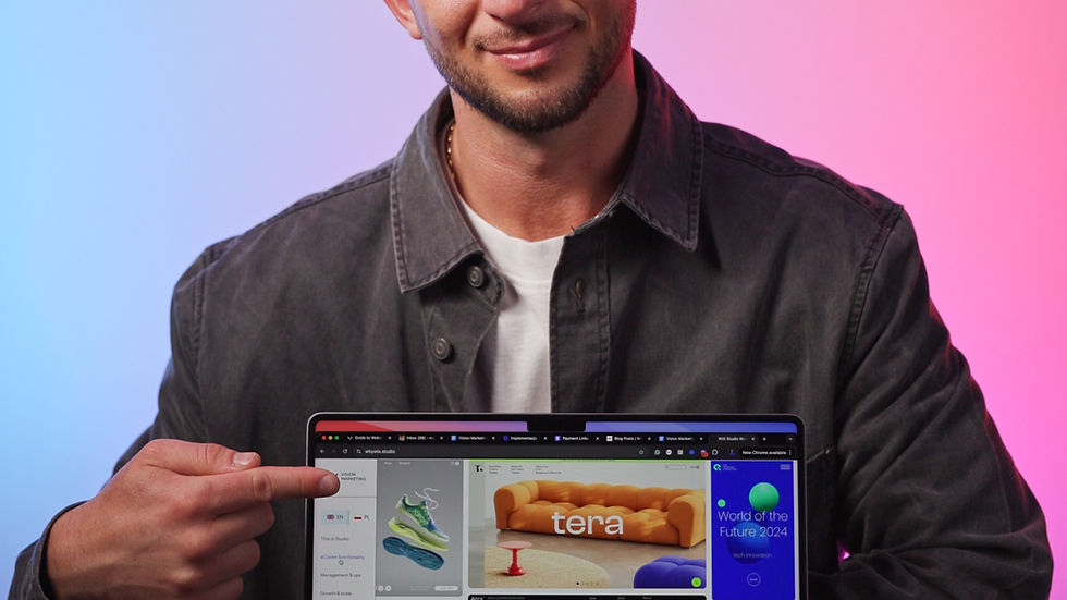 Man in a gray jacket smiles, pointing at a laptop screen with various colorful website thumbnails. Background is blue and pink gradient.