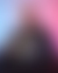 Man in a gray jacket smiles, pointing at a laptop screen with various colorful website thumbnails. Background is blue and pink gradient.