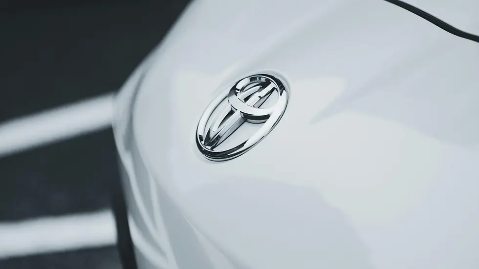 Close-up of a chrome Toyota badge on the glossy white bodywork of a car.