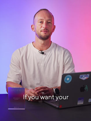 Man in a white shirt at a desk with a laptop and a "Certified Web Design Expert" plaque. Gradient blue-pink background.