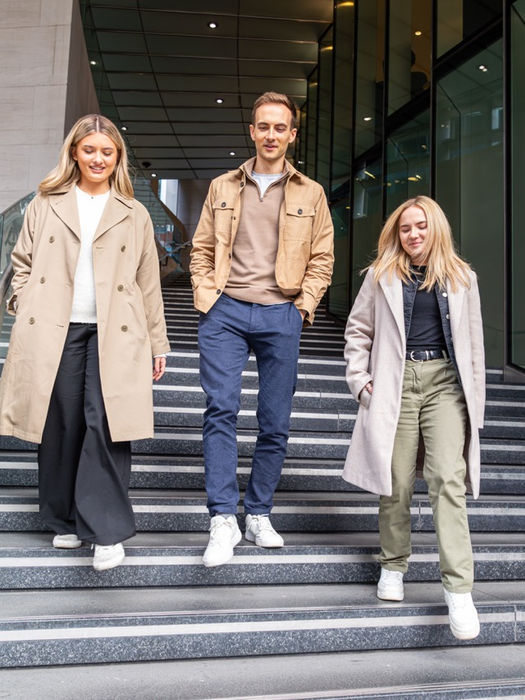 Three people walking down modern outdoor city stairs.