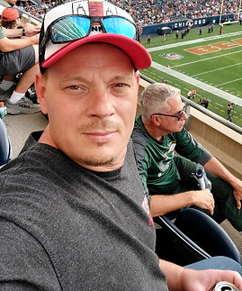 "Image of Andriy Maslovsky, CEO of Maslo Construction, enjoying a Bears game. He's casually dressed, capturing the spirit of leisure and community involvement, reflecting a balance between professional dedication and personal interests