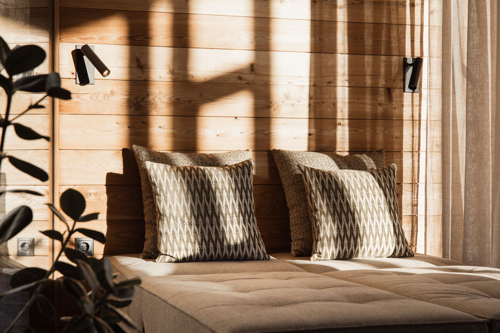 Detailaufnahme des Wellnessbereichs-Bettes im Asterhof Zillertal, mit Kissen und der Holzverkleidung im Hintergrund.