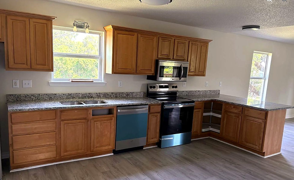 Natural wood raised-panel kitchen cabinets with speckled countertops and a black range