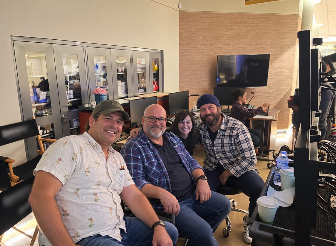 Dr. Brandy seated with a group beside production monitors.