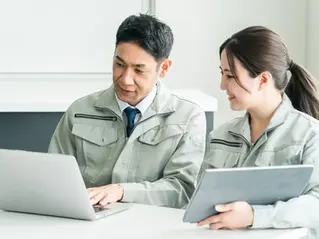 パソコンで作業をする作業服の男性