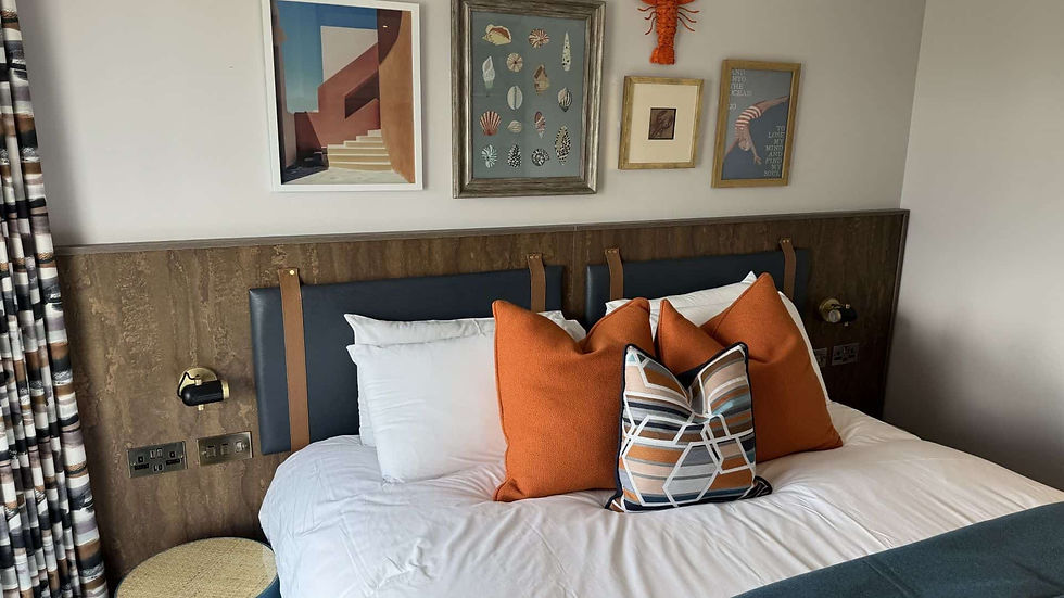 Bespoke wood wall-panel headboard with integrated hanging navy leather cushions, orange accent pillows, and built-in reading lights by Target Furniture for Waterside Hotel