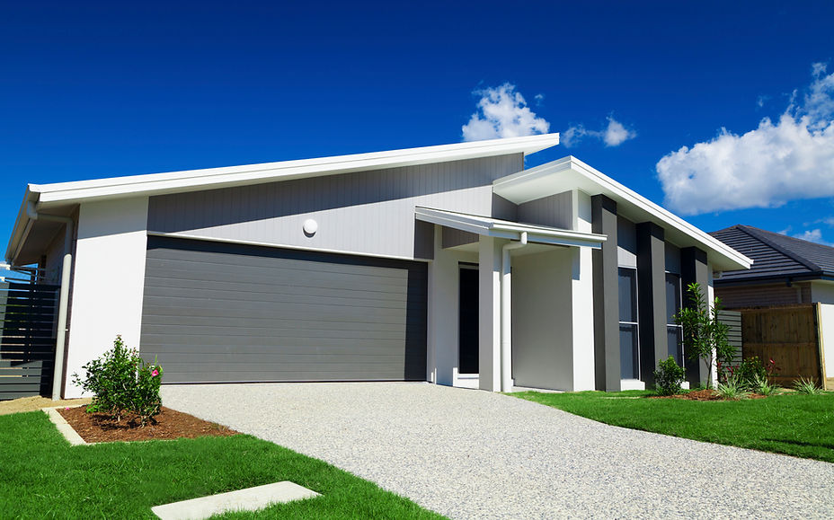 A modern single-storey house with a double garage and grey and white wall cladding, seen from the driveway