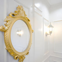 A golden mirror hanging on the white wall of a room