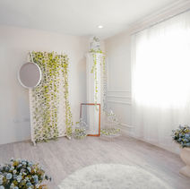 The corner of the white room where the sun shines brightly on the white curtains. A wall of vines, white Ionic Column at the corner of the room. A white furry carpet and a white vase placed on the center.