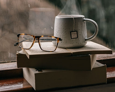 Mug and reading glasses resting on a stack of books