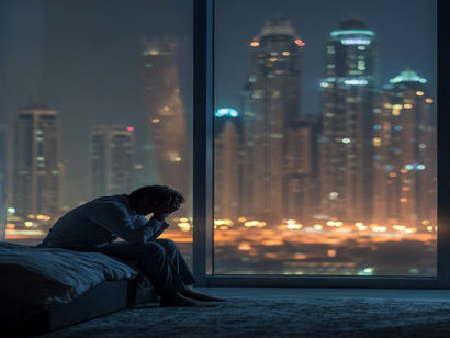  Exhausted Dubai professional sitting on his bed not able to sleep in his apartment in Dubai Marina